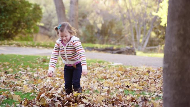 Little girl throwing autumn leaves