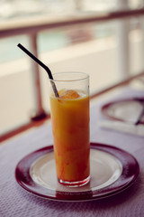 Glass of refreshing cool mango lassi sweet Indian drink over restaurant table light background