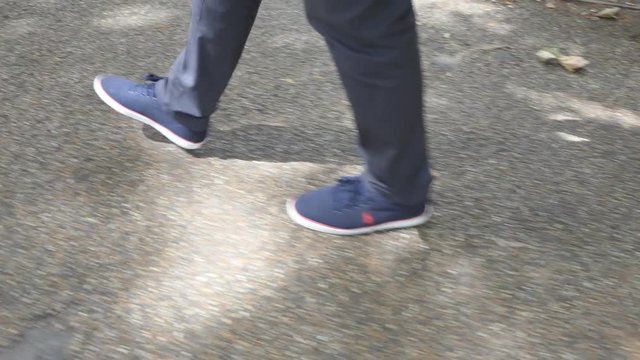 Close-up of male legs. The man is walking along the sidewalk.