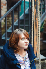 Fototapeta premium thoughtful white caucasian woman sitting on a swing in a jacket