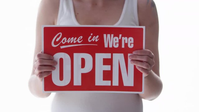 Woman holding a come in we're open sign