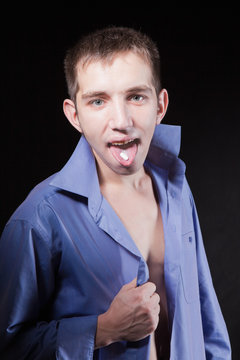 Young handsome man is taking a pill on tongue
