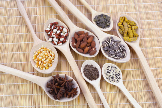 Wooden spoons group on mat with healthy seeds, nuts and spices