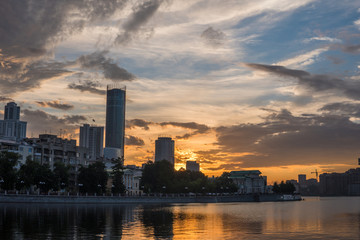 Obraz premium Yekaterinburg city center on sunset. City pond view, amazing clouds and sky. High buildings, skyscrapers on the embankment of the river Iset