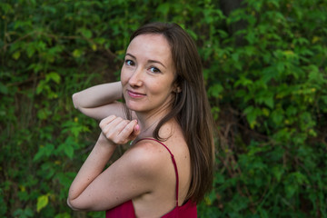 Young woman portrait in a summer forest in the mountains. Pretty girl in red dress in summertime