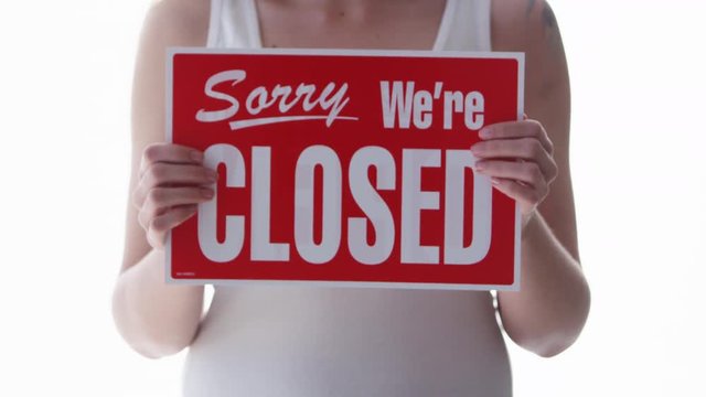 Woman holding a Sorry we're closed sign