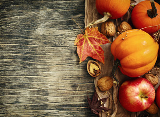 Autumn pumpkins and apples with fall leaves on wooden background with copy space. Autumn composition