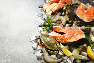 Fototapeta na wymiar Fresh seafood: salmon steak, shrimps and crabs on stone background with copy space