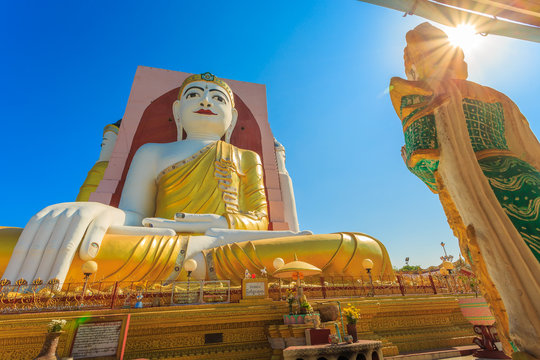 Illuminating Sunlight, Kyaik Pun Buddha the big Four Seated Buddha statues Shrine Sitting Back to Back of Four Directions on blue sky, Bago (Pegu), Myanmar.