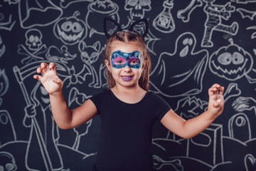 Girl in a cat costume on dark background with Halloween illustrations.