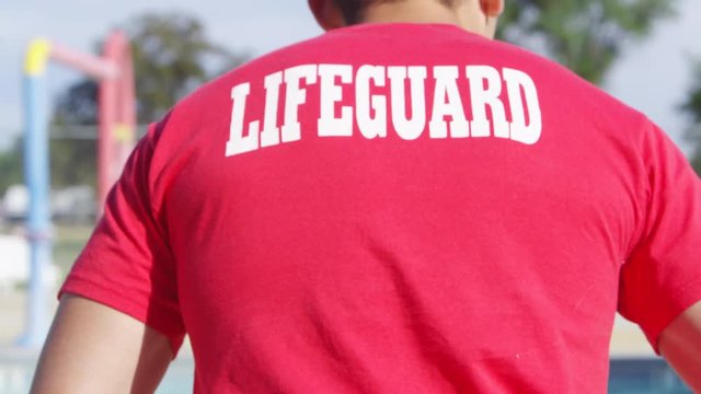 Young lifeguard jumping into the pool