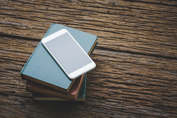 Fototapeta premium Book with smartphone on wood vintage tone