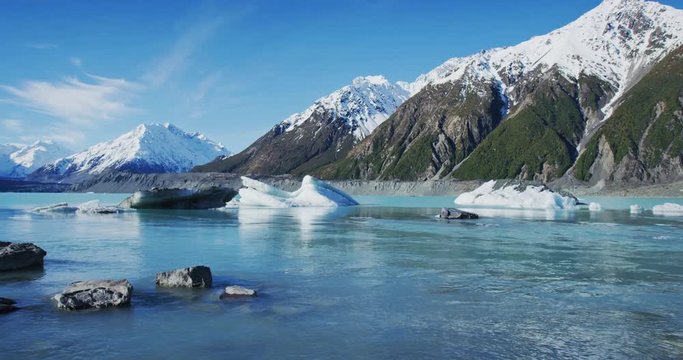 Icebergs Floating in Glacier Lagoon with Snowy Mountains in Background