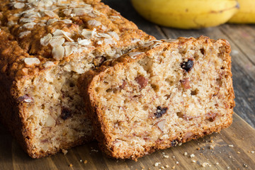 Homemade banana bread loaf with walnuts sliced on wooden cutting board. Closeup view, horizontal