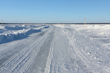 Fototapeta na wymiar Ice road in snow on the frozen water reservoir in the winter, the Ob River, Siberia, Russia