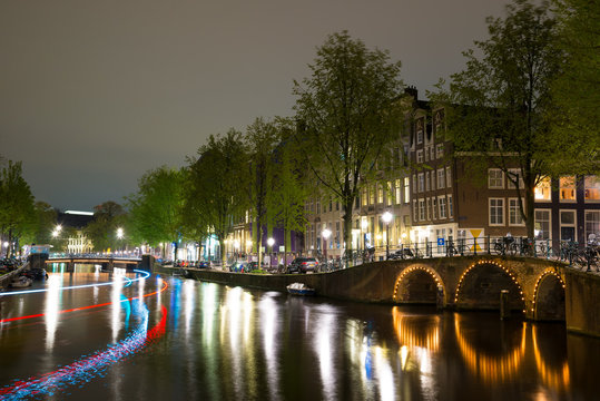 Night view of Amsterdam cityscape with canal, bridge and houses in the evening