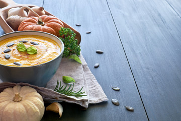 Spicy pumpkin creme soup with ginger, onion and garlic on blue wood