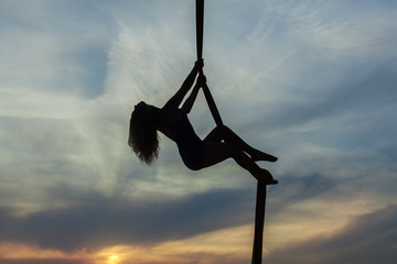 Woman aerial acrobat climbs up the rope.