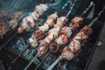 Grilled kebab cooking on metal skewers (grill). Roasted meat cooked at barbecue with smoke. Close up BBQ fresh pork meat chop slices. Traditional eastern dish, shish kebab