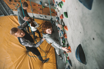 Little boy climbing wall at gym