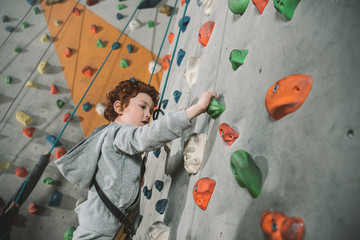 Little boy climbing wall at gym