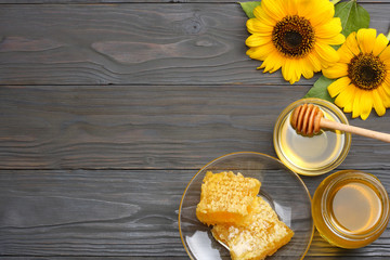 Sunflower with honey, Honeycomb and honey dipper on dark wooden table. Top view with copy space