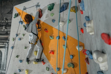 Little boy climbing wall with grips