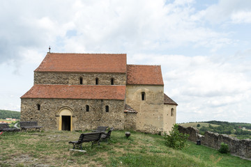Fototapeta na wymiar Cisnadioara, Transylvania, Romania. Fortified medieval church on top of rock hill in Cisnadioara near Sibiu, Transylvania, Romania. Cloudy summer day.