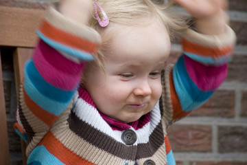 Fototapeta na wymiar Fröhliches kleines Mädchen freut sich draußen auf der Parkbank