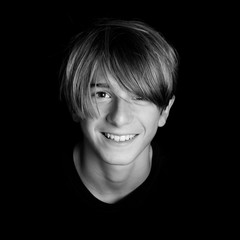 young blonde smiling guy portrait on black background - black and white photo