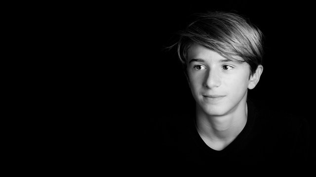young blonde guy portrait on black background - black and white photo