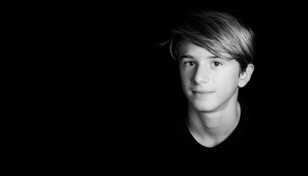 young blonde guy portrait on black background - black and white photo