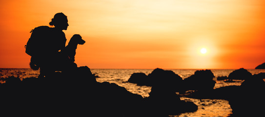 Woman with a dog hiking along the seashore