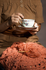Crochet and the woman's hands with tea cup. The concept of hobbies and leisure.