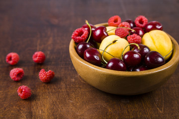 Ripe berries in a plate on a wooden table.