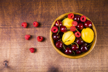 Ripe berries in a plate on a wooden table.