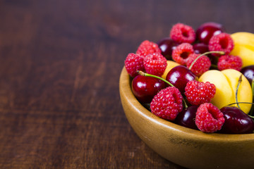 Ripe berries in a plate on a wooden table.