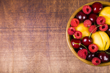 Ripe berries in a plate on a wooden table.