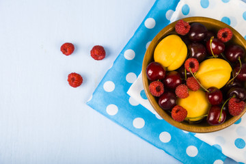 Ripe berries in a plate on a wooden table.