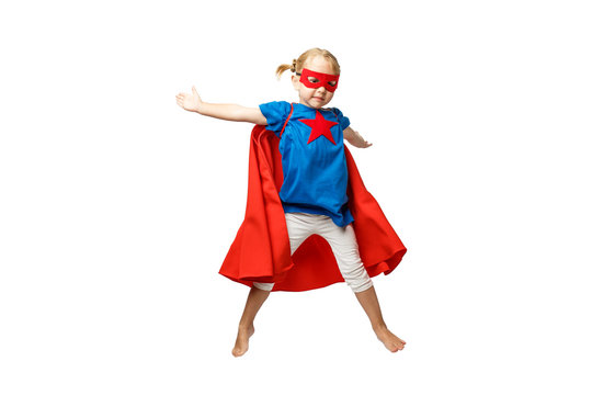 Very excited little girl dressed like superhero jumping isolated on white background.