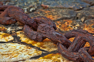 Rusty chain lying on the swab close to a marina