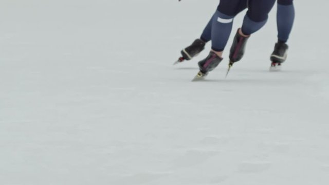 Low angle shot with slow motion of unrecognizable speed skaters racing on ice track