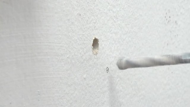 Close up shot electric driller bit spin to drilling cement concrete white wall for hold with ambient sound