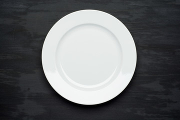 Empty plate on dark black wooden background. Top view with copy space