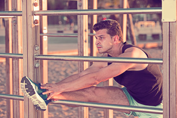 Man stretching on wall bars on beach