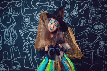 Girl in a witch costume on dark background with Halloween illustrations.