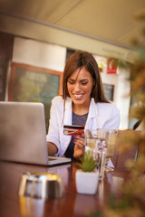 Young woman using laptop and credit card. Girl buys it through a credit card.