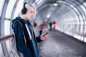 Obraz premium Young student listening to music in big headphones in the subway tunnel