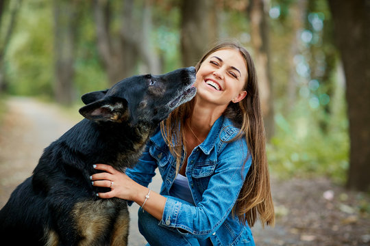 Portrait of a young girl with a dog hugging in the park. German shepherd with a woman.