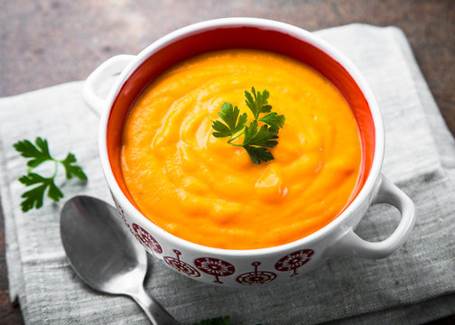 Carrot cream-soup on dark table.